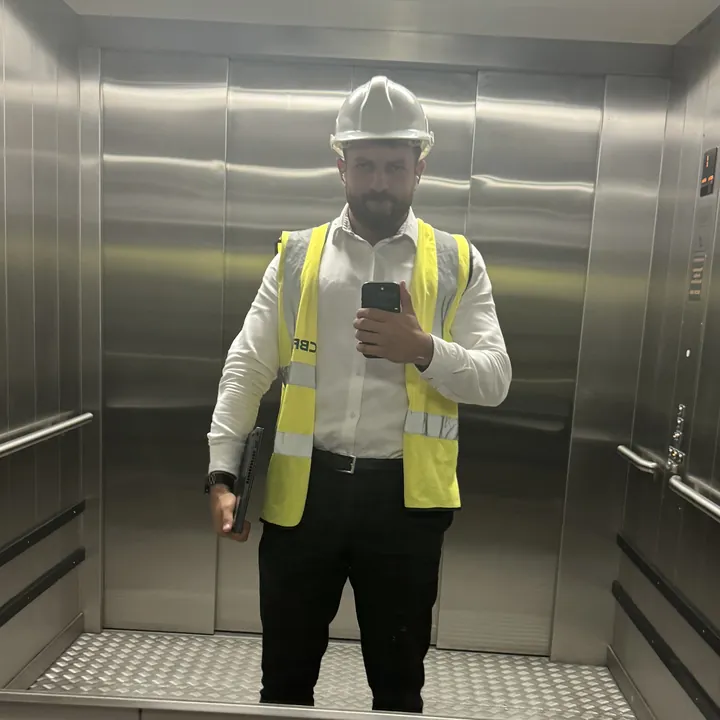 Anwar in a hard hat and hi-vis on a site visit