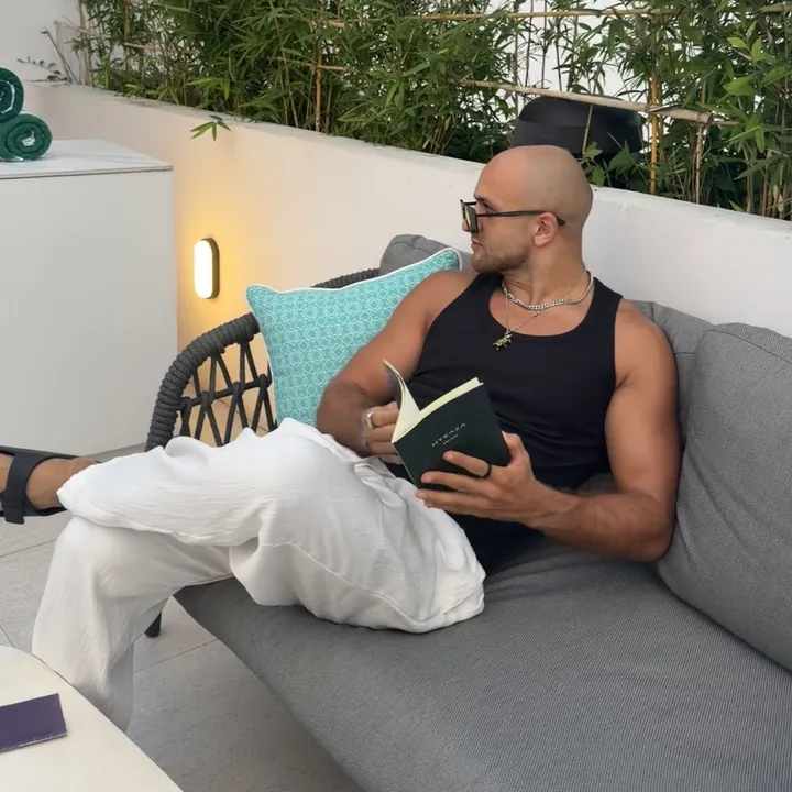 Anwar reading a book on a sofa in Bali